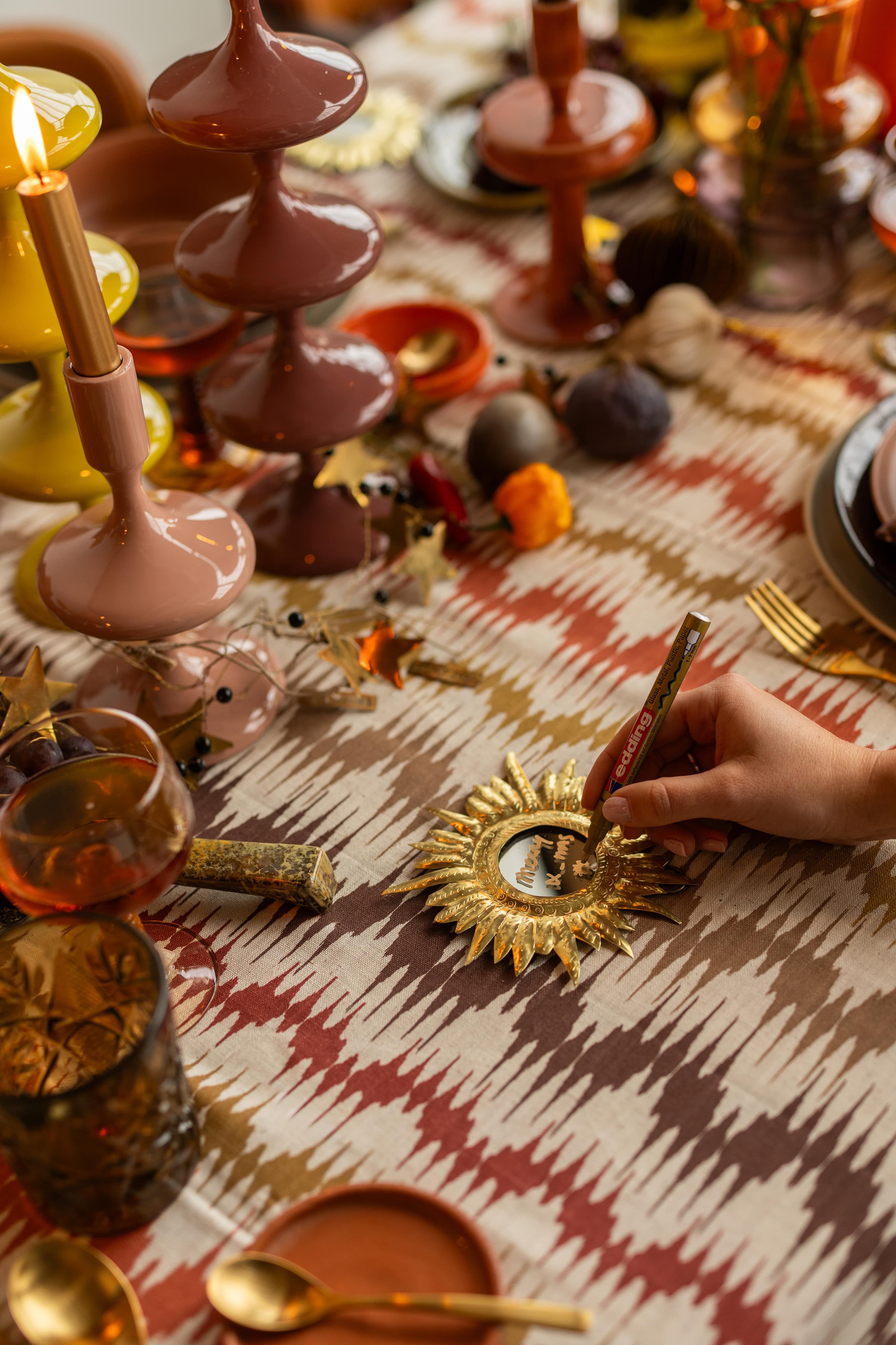 Een hand met een stift schrijvend op een goude spiegel